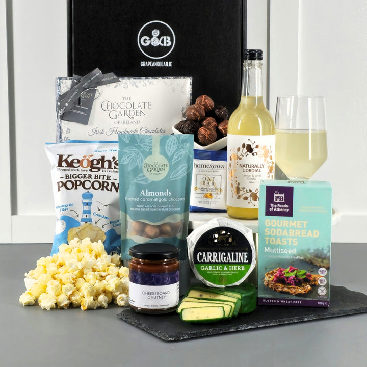 Black gift box with cordial, cheese, chutney, chocolate, popcorn, cordial, sodabread toast.