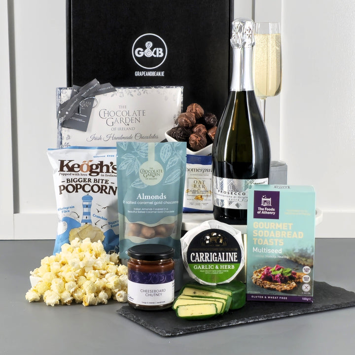Gourmet gift box with popcorn, chocolate,  cheese, chutney, soadbread and prosecco in a black gift box
