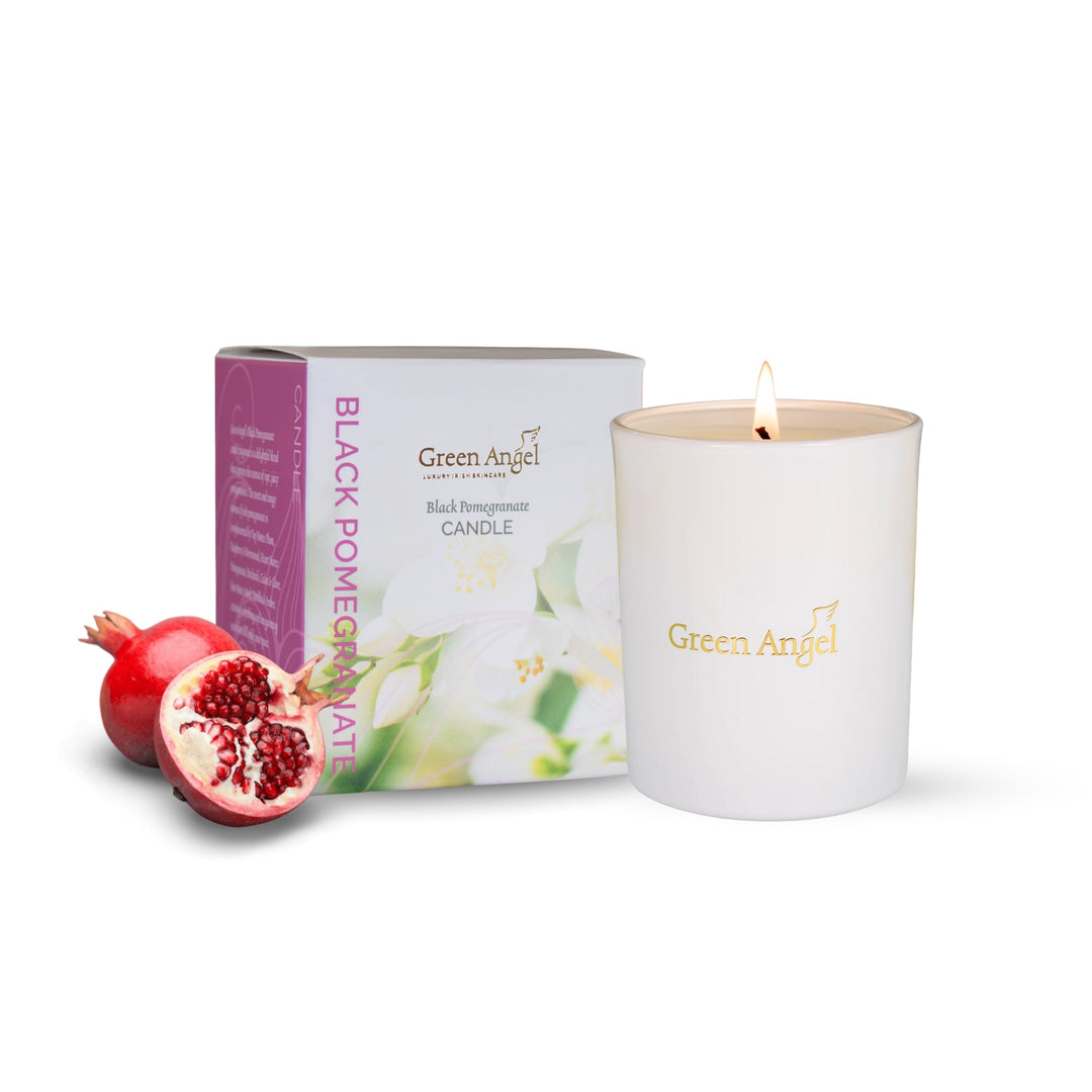 Green Angel candle with packaging and pomegranate fruit on a white background