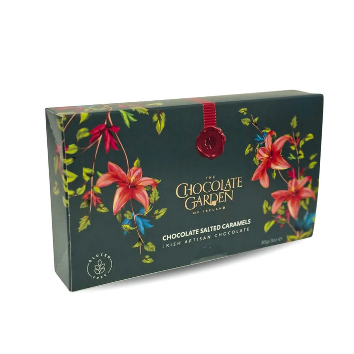 The Chocolate Garden of Ireland chocolate box featuring a dark green background with red lilies, green leaves, and a red wax seal, on a white background.