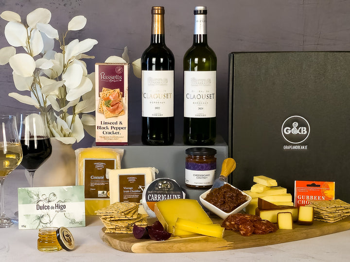 Red and white Wine, cheese, crackers, and other snacks on a table with a decorative background.