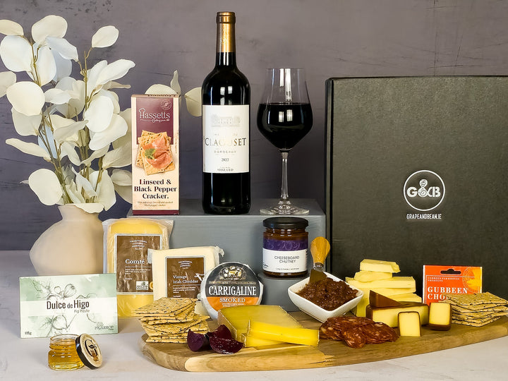 Gourmet food hamper with cheese, crackers, fig paste, red wine, chorizo, chutney in a black gift box.