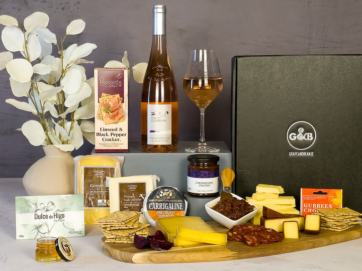 Gourmet food  with cheeses, crackers, chutney, chorizo , fig paste and a bottle of rose wine in a black gift box 